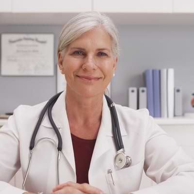 Photo of a female trusted physician wearing a lab coat and with a stethoscope.